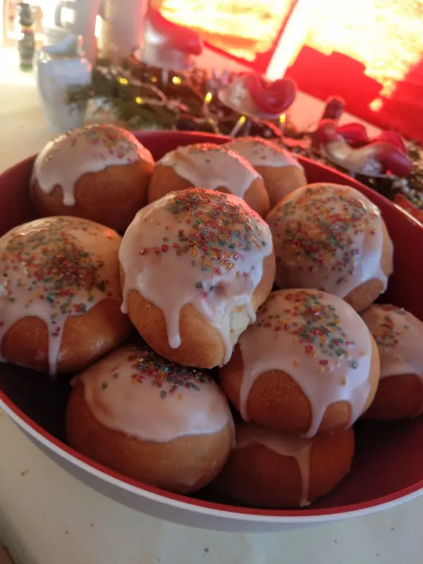 Eine Schüssel mit Berliner, überzogen mit Zuckerguss und bunten Streuseln, steht festlich auf einem Tisch.