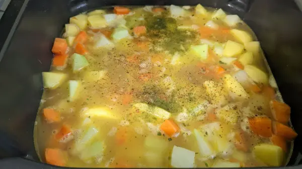 Ein Gemüseeintopf aus der Heißluftfritteuse kocht in einem Topf, gefüllt mit buntem Gemüse und Gewürzen.