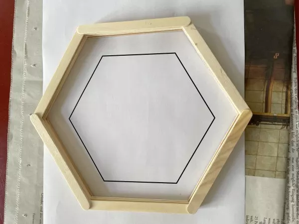 Hier sieht ein Hexagon, das bereits mit mehreren Lagen Eisstielen zusammengeleimt wurde.