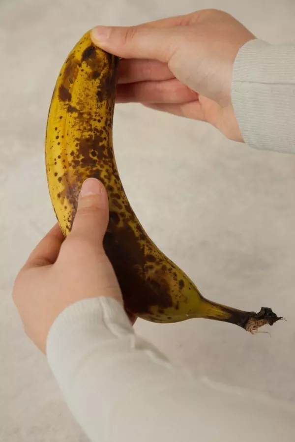 Die Banane kannst du ganz einfach schälen. Pack sie am unteren Ende und drücke Daumen und Zeigefinger zusammen.  Jetzt öffnet sich die Schale und du kannst sie einfach abziehen.