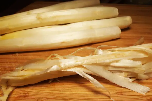 Gestreifter, geschälter Spargel liegt auf einem Holzbrett und sieht frisch aus, ideal für die Lagerung.