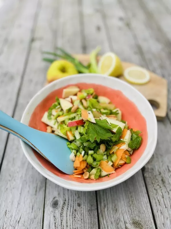 Schüssel mit frischem Apfel-Sellerie-Salat: Datteln, Chili, Erdnüsse und Zitrone geben dem Salat eine besondere Note.