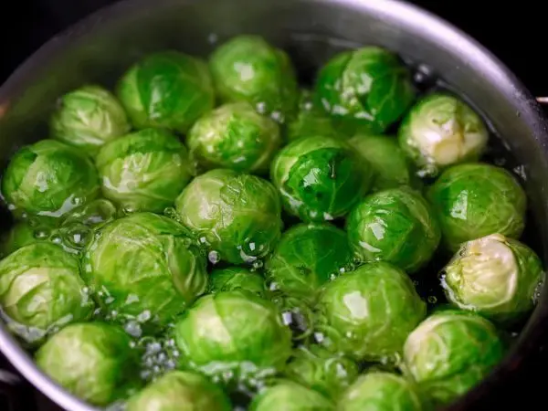 Rosenkohl kocht sprudelnd in einem Topf, zeigt frische grüne Köpfe in klarem Wasser, ideal zum Zubereiten.