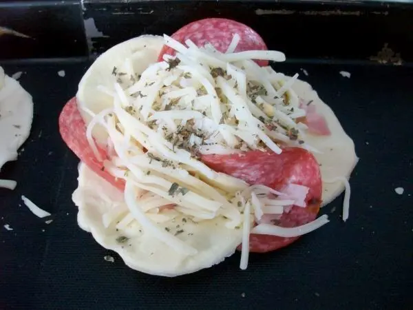Mit Eigelb den Blätterteiganteil bestreichen. Blume mit geriebenem Käse, die Käsesorte nach eigenem Geschmack bestreuen.