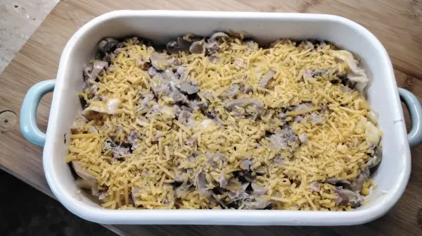 In die gebutterte Auflaufform kommen die Tortellini. Mit der Béchamelsoße bedeckten, oben den geriebenen Cheddar-Käse aufstreuen. 
