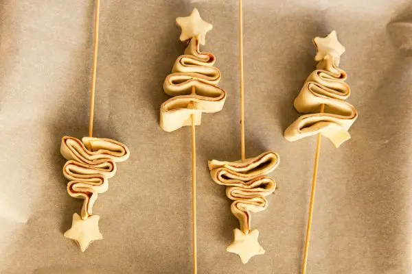 Lege die Blätterteig-Bäume auf ein Backblech und lass dabei ausreichend Platz. Der Blätterteig wird im Ofen noch aufgehen. Blätterteig-Tannenbäume am Spieß: Einfaches Rezept für süße oder herzhafte Weihnachts-Snacks, hübsch als Fingerfood angerichtet.