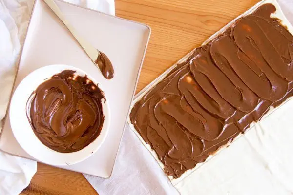 So bereitest du im Handumdrehen süße Blätterteig-Tannenbäume zu: Blätterteig mit Schokocreme bestreichen – perfekt für Weihnachten! Blätterteig mit Nutella bestreichen – so startest du die süße Variante der Blätterteig-Tannenbäume am Spieß.