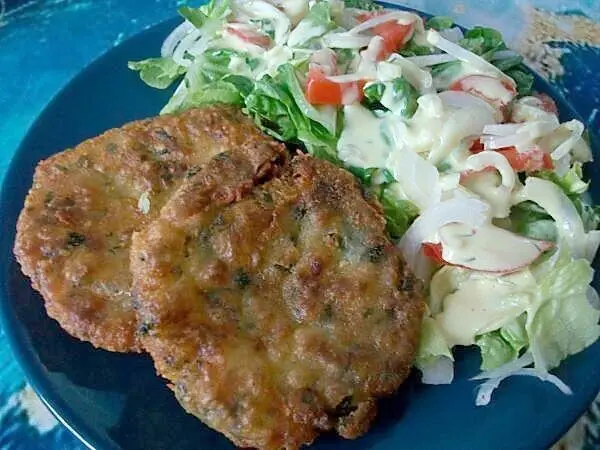 Die selbstgemachten Kartoffelküchlein mit Mozzarella auf einem Teller serviert mit frischem Salat als Beilage.