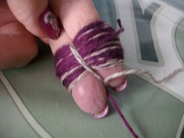 Für die Bommel, Wolle um zwei Finger wickeln, mittig mit einem Faden festbinden und die Schlaufen aufschneiden.