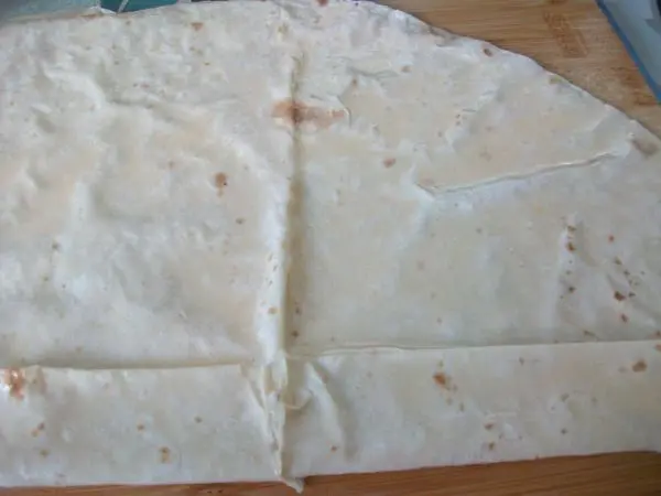 Das Yufkablatt mit der Milch-Ei-Mischung feucht bestreichen und zur Hälfte klappen, dann unten ca. 2–3 cm umschlagen.