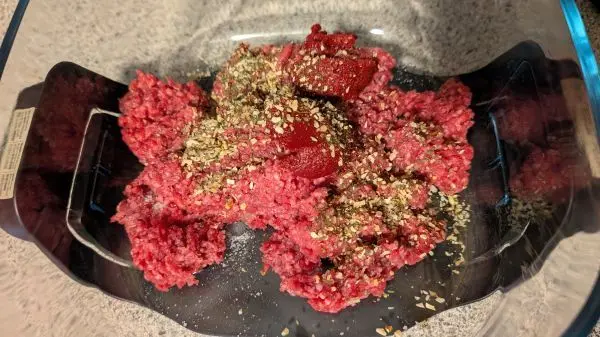 Rinderhack, Butteröl, Gewürzmischung und Tomatenmark in die große Glasschüssel geben und miteinander vermengen. Rinderhack, Butteröl, Gewürzmischung und Tomatenmark in die große Glasschüssel geben und miteinander vermengen.