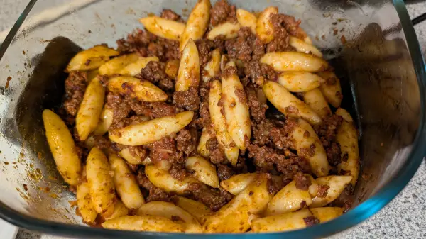 Fertig mit dem Garen! Jetzt wird das Ganze auf zwei flache Teller verteilt, damit wir gleich essen können. Hausgemachte türkische Manti nach schwäbischer Art: Omas Schupfnudeln mit würziger Hackfleischfüllung aus dem Ofen, so schmeckt Fusion!