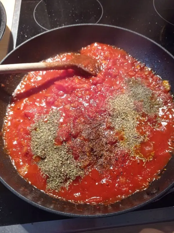 Die gehackten Tomaten fügt man nun zusammen mit den Gewürzen ebenfalls zu den angerösteten Zutaten dazu. 