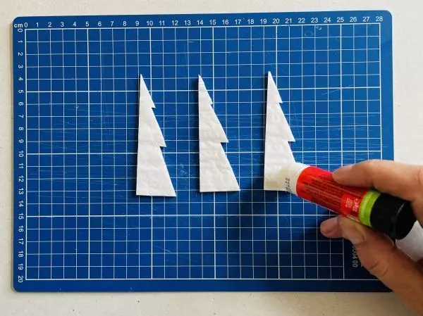 Drei halbe Bäumchen aus Wabenpapier werden mit einem Klebestift zunächst aufeinander geklebt. Drei halbe Bäumchen aus Wabenpapier werden mit einem Klebestift zunächst aufeinander geklebt.
