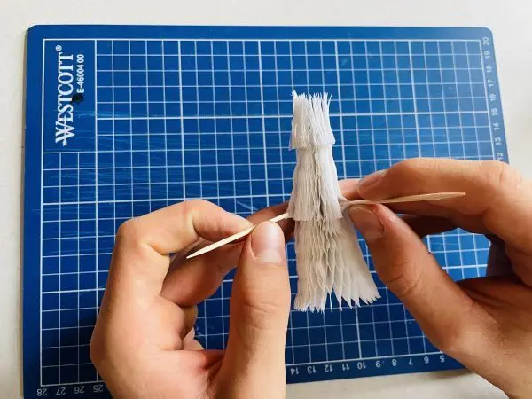 Mithilfe von zwei Zahnstochern lässt sich der Tannenbaum aus Wabenpapier einfacher auffächern. Mithilfe von zwei Zahnstochern lässt sich der Tannenbaum aus Wabenpapier einfacher auffächern.