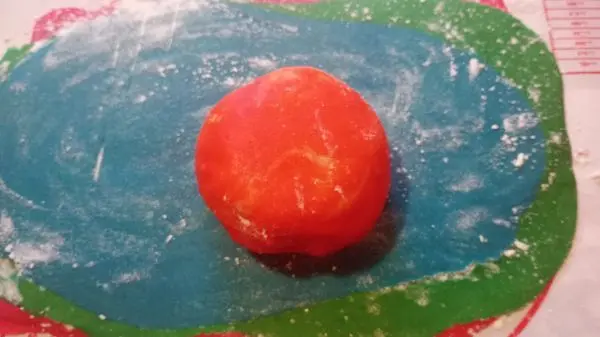 Dann rolle ich alle Kugeln vorsichtig übereinander aus, sodass ich schöne Teiglagen bekomme.