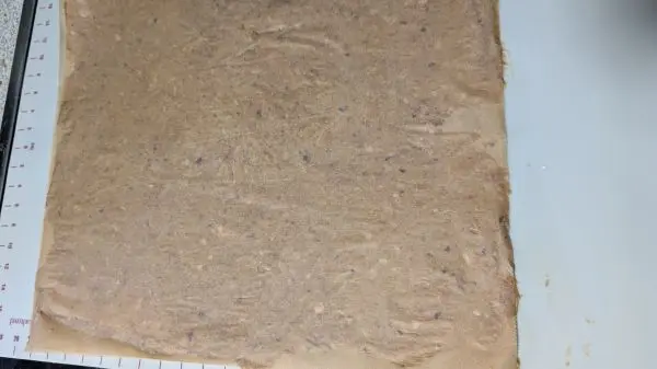 Ein weiteres Blatt vom Backpapier gibt man obendrauf & rollt den Teig mit einer Teigrolle komplett aus.