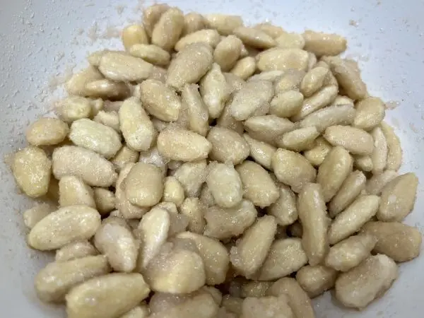 Mit dem Airfryer gelingt Dir dieser knusprige Klassiker: Gebrannte Mandeln selbst gemacht, ganz einfach und ohne großen Aufwand. Die Mandeln mit Zucker, Vanillezucker, Zimt und Wasser mischen, sodass alle Mandeln gut mit der Zuckerschicht bedeckt sind.