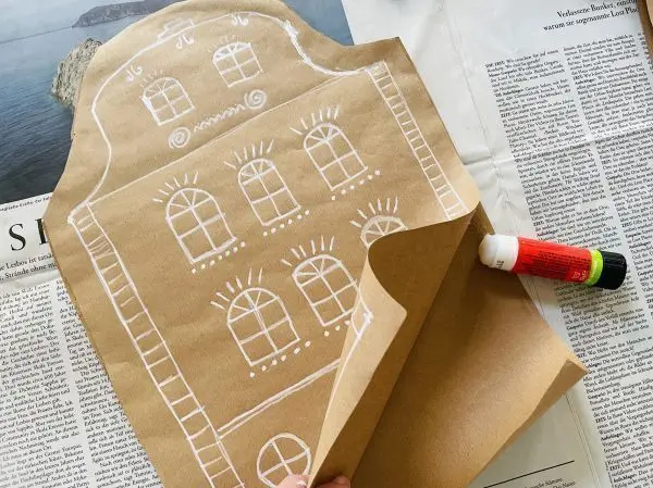 Das Geschenk wird hineingelegt und dann werden die Ränder des Packpapiers mit Lebkuchenhaus-Zeichnung zugeklebt.