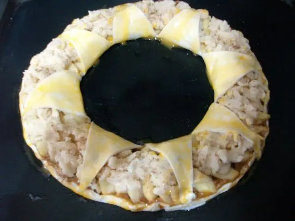 Nun werden diese Bl&auml;tterteigspitzen &uuml;ber den &Auml;pfeln, mit Eigelb bestrichen. Dann gibt man den Apfelring bei 200 Grad in den Ofen.