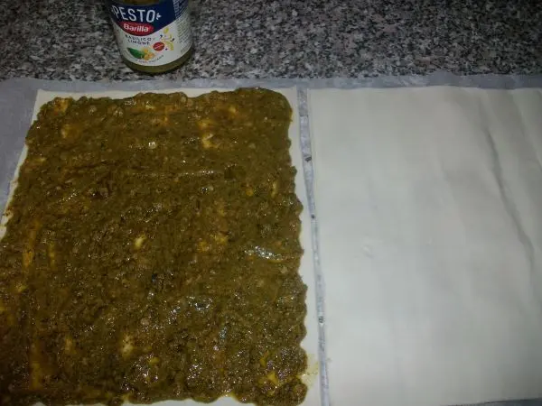 Die eine Hälfte vom frischen Blätterteig gleichmäßig dick mit ca. vier EL Pesto bestreichen. Die eine Hälfte vom frischen Blätterteig gleichmäßig dick mit ca. vier EL Pesto bestreichen.