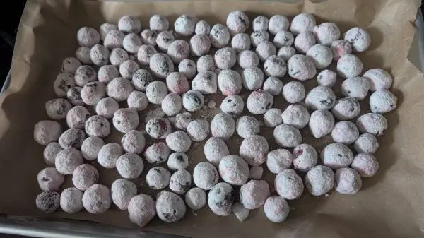 Backblech mit Backpapier auslegen und die gepuderten Cranberries darauf verteilen.