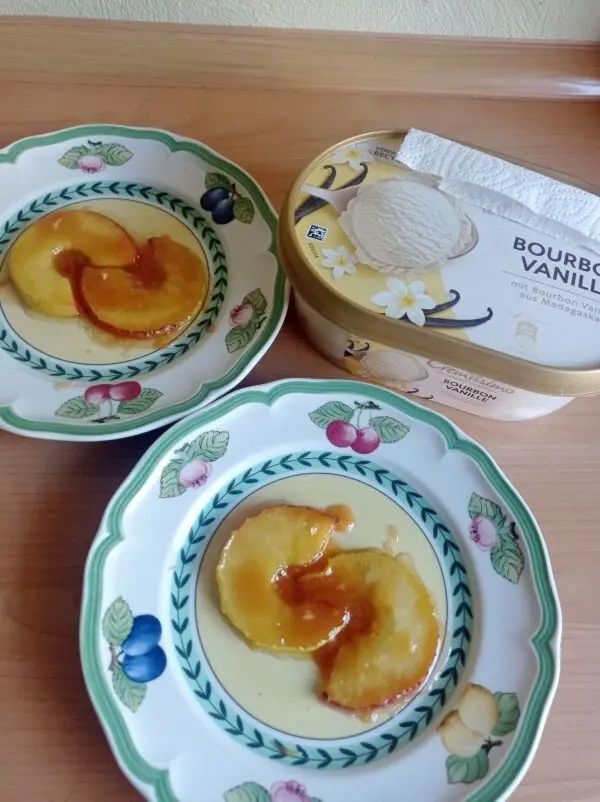 Die Apfelscheiben werden in der Karamellmasse gewälzt und dann auf flache Dessertteller gelegt und mit Vanilleeis serviert. Die Apfelscheiben werden in der Karamellmasse gewälzt und dann auf flache Dessertteller gelegt und mit Vanilleeis serviert.