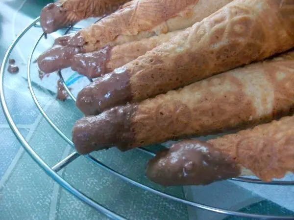 Damit unten an der Öffnung nichts ausläuft, tauche ich die Eiserkuchen mit der Spitze kurz in erhitzte, flüssige Schokolade. Damit unten an der Öffnung nichts ausläuft, tauche ich die Eiserkuchen mit der Spitze kurz in erhitzte, flüssige Schokolade.