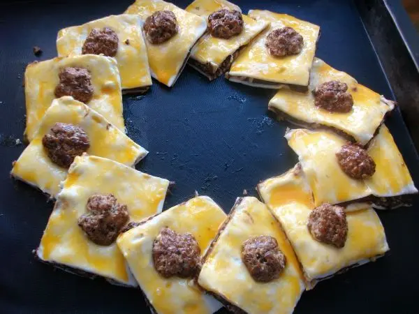 Die Teilchen überlappend im Kreis zu einem Kranz aneinanderlegen. Mit Eigelb bestreichen und die 12 Walnüsse verteilen. Die Teilchen überlappend im Kreis zu einem Kranz aneinanderlegen. Mit Eigelb bestreichen und die 12 Walnüsse verteilen.