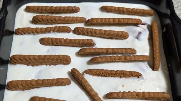 Die zweite H&auml;lfte vom Joghurt dar&uuml;ber geben, glattstreichen und mit den Lotus Biscoff Keksen best&uuml;cken.