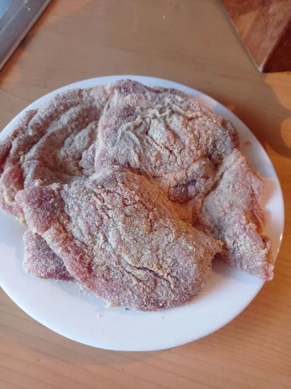 Die Schweinenacken-Steaks werden geklopft. Man w&uuml;rzt mit Pfeffer und Salz. Dann werden die Steaks noch d&uuml;nn paniert.