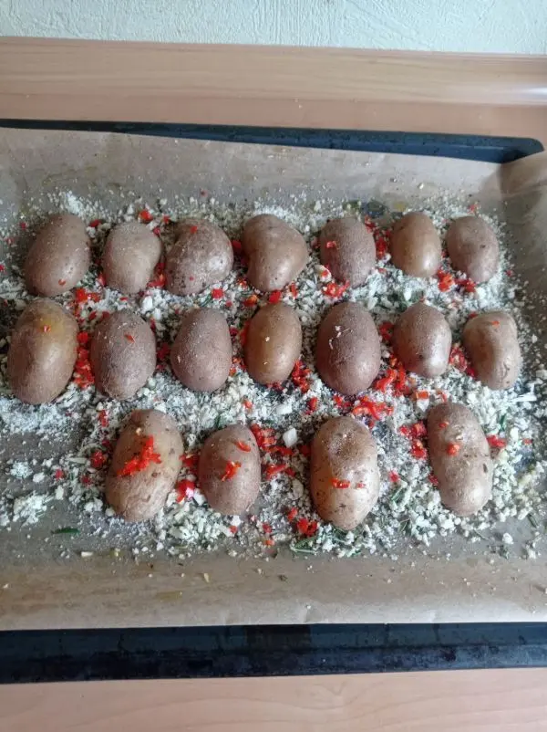 Mit der Schnittseite dr&uuml;ckt man die halbierten Kartoffeln in die Panko-Mischung, w&uuml;rzt mit Pfeffer und Salz und den Peperoni.