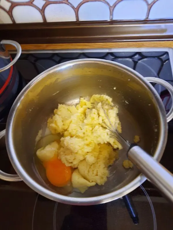 Hier sieht man, wie ein Ei in die Grie&szlig;masse einger&uuml;hrt wird und gleich darauf folgt das zweite Ei.