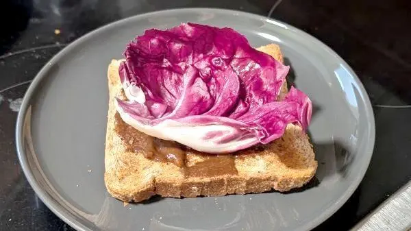 Nachdem ich das Brot mit Senf bestrichen hatte, habe ich es mit einem Salatblatt belegt.