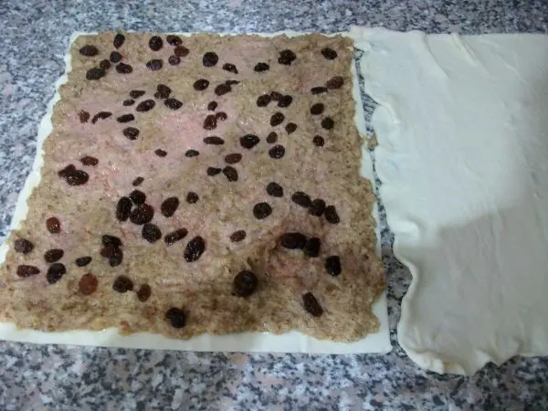 Den frischen Blätterteig ausrollen, halbieren und auf die Hälfte die Walnussmischung aufstreichen, dann die Rosinen verteilen. Den frischen Blätterteig ausrollen, halbieren und auf die Hälfte die Walnussmischung aufstreichen, dann die Rosinen verteilen.