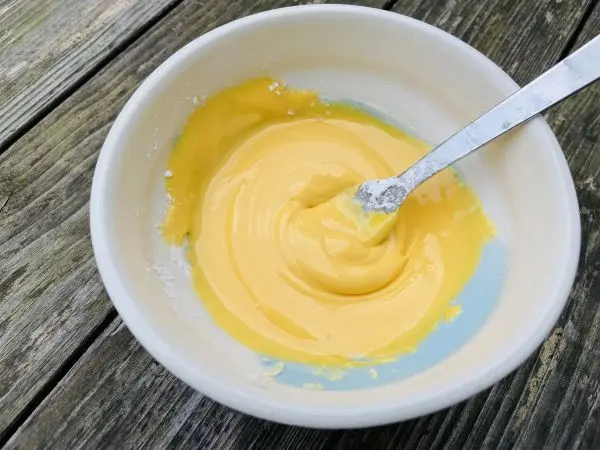 Der Zuckerguss f&uuml;r die Osterpl&auml;tzchen wird mithilfe von Lebensmittelfarbe so eingef&auml;rbt, dass er das typische Eidotter-Gelb annimmt.