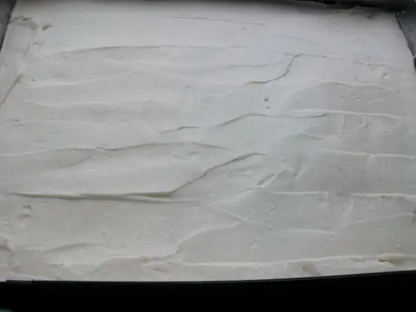 Nun einen Tortenrand fest um den Schoko-Bananen-Kuchen geben und die Schmandcreme gleichm&auml;&szlig;ig aufstreichen.