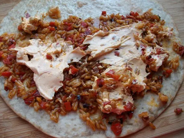 Auf den halben Wrap dann ca. 2 EL vom Djuvec Reis verteilen, etwas Frischk&auml;se dazu und in der H&auml;lfte zusammenklappen.