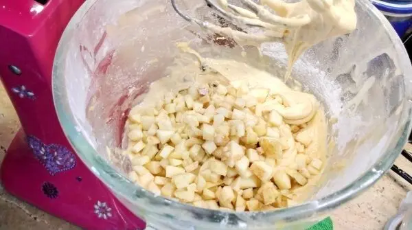 Die kleingeschnittenen &Auml;pfel werden in Teig f&uuml;r den Apfelkuchen im Glas einger&uuml;hrt.