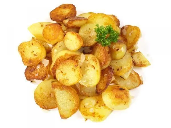 Bratkartoffeln, goldbraun gebraten, mit einem Zweig Petersilie auf einer weißen Platte angerichtet, ideal als Beilage.