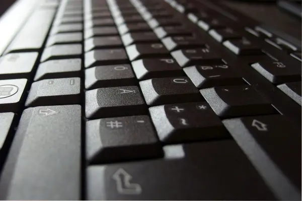 Eine Computertastatur liegt schräg auf einem Tisch, bereit zur Reinigung, ihre Tasten sind deutlich sichtbar.