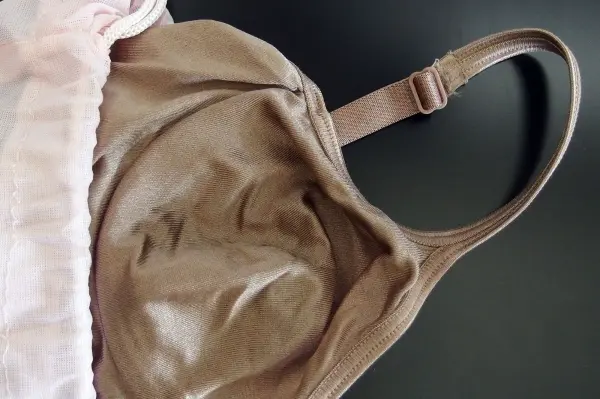 Ein Bügel-BH liegt auf einem dunklen Tisch und zeigt die Form und Struktur des Stoffes, bereit für die Waschmaschine.