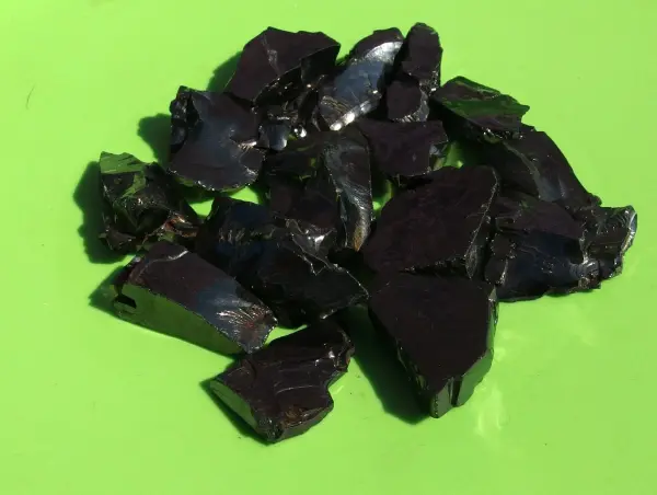 Schwarze Aquariumsteine liegen auf grünem Untergrund in der Sonne, um gereinigt und aufgehellt zu werden.