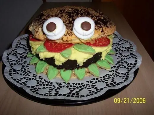 Eine Big Mac Torte mit dekorativen Augen liegt auf Spitzendeckchen, wirkt wie ein Burger mit Schichten von Creme und Deko. Datum: 21.09.2006.