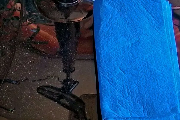 Auf einem staubfreien schwarzen Möbelstück liegt ein blauer Lappen, bereit zum Wischen. Die Umgebung ist eher dunkel gehalten.