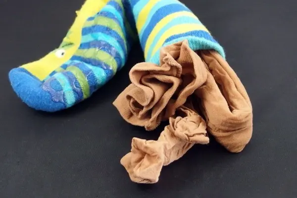 Feinstrumpfhosen liegen in bunten Socken auf einem dunklen Untergrund, bereit zum Waschen in der Maschine.