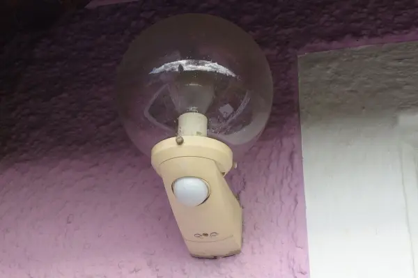 Ein Bewegungsmelder ist an einer Wand montiert und erkennt Bewegung, um eine Lampe zu aktivieren.