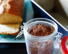 Kuchenform mit Kakaopulver ausstreuen