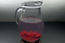 Aromatisiertes Wasser: Zerdrückte Himbeeren in einen Krug mit Wasser