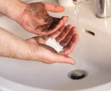 Ölverschmierte Hände mit Waschpulver reinigen